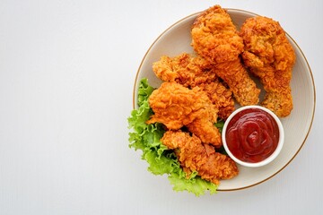 Crispy Fried chicken in a white plate with tomato sauce on white background table, free copy space