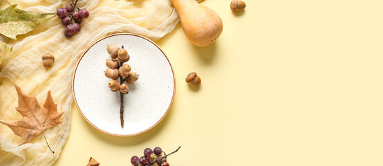 Autumn table setting with pumpkin, grapes and chestnuts on yellow background
