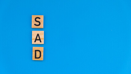 Seasonal affective disorder - text of wooden blocks on blue bright background. Concept of depression mood stress and anxiety. SAD wellbeing 