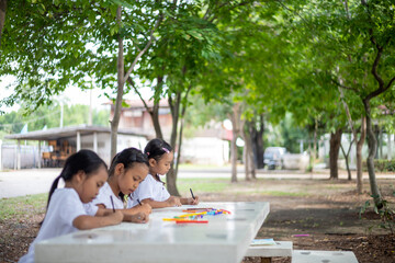 Three young girls are sitting at a table with markers and coloring books.