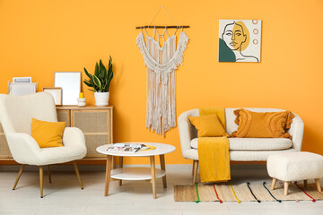 Stylish interior of living room with white armchair, cozy sofa and coffee table