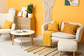 Stylish interior of living room with white armchair, cozy sofa and coffee table