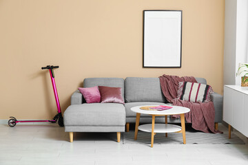 Pink electric scooter near sofa in stylish living room
