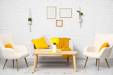 Interior of living room with comfortable sofa, armchairs and vase of flowers on coffee table