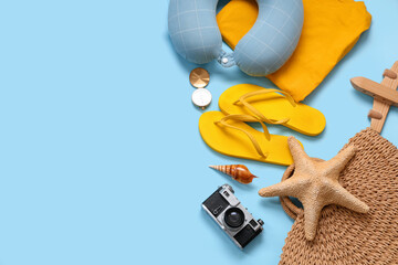 Travel pillow, photo camera and beach accessories on blue background
