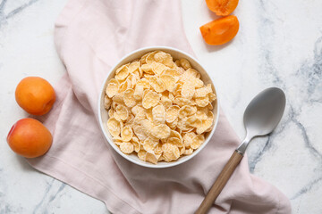 Apricots, napkin and bowl with cornflakes on marble background