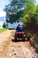 A red ATV is parked on a dirt road with a view of the mountains.