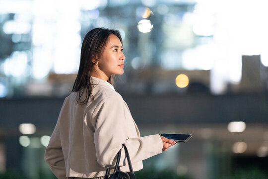 スマホを片手に夜の雑踏にいる女性