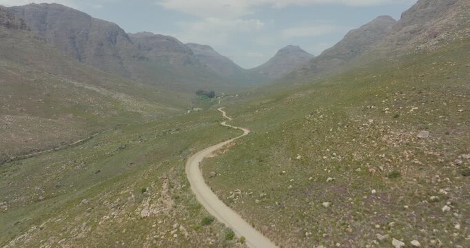 Drone flies high above a road in a rocky landscape in Cederberg Wilderness Area south africa - you can see a road surrounded by high mountains