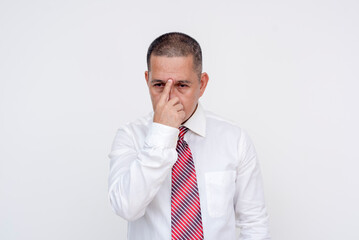 A restless middle aged asian manager fidgeting his glabella, coping with a stressful day. Isolated on a white background.