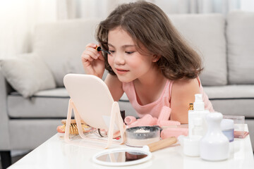 Happy children sit in front of a mirror makeup on face. Girl applying makeup. Advertisement, lifestyle , cosmetics, makeup accessories, beauty activity, beautician, talent, love beauty