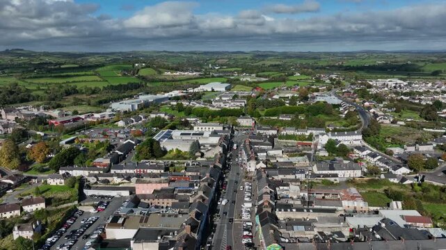 Carrickmacross Town, County Monaghan, Ireland, November 2022. Drone panoramic pullback and clockwise orbit above main street leading into center of the rural market town on a sunny day.