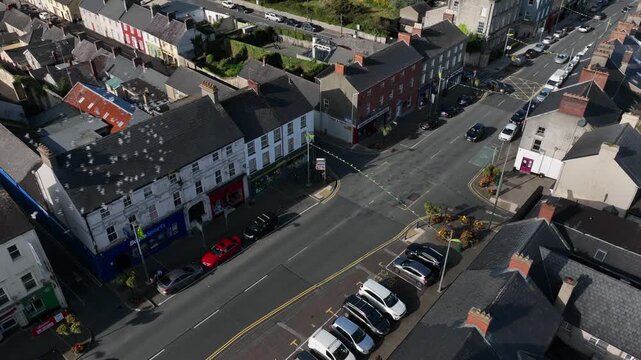 Carrickmacross Town, County Monaghan, Ireland, November 2022. Drone pushes forward above Main Street at an angle as birds circle and cars drive through the rural market town on a sunny afternoon.