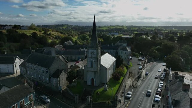 Carrickmacross Town, County Monaghan, Ireland, November 2022. Drone orbits clockwise around St Finbarr&rsquo;s Church of Ireland backlit in shadows pulling backwards as cloud passes above.