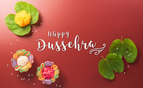 Happy Dussehra. Yellow flowers, green leaf and rice on dark paper background. Dussehra Indian Festival concept.