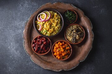 An assortment of vibrant, flavorful vegetarian Pakistani and Indian dishes, including biryani rice, served in bowls on a rustic platter