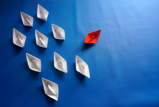 Business For Innovative Solution Concept. Group Of White Paper Ship In One Direction And One Red Ship Pointing In Different Way 
