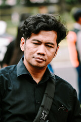 A Southeast Asian man closes his eyes, appearing calm and reflective.