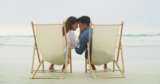 Chair, love and beach couple relax together, connect and bond on tropical island, honeymoon or freedom trip. Forehead touch, back and outdoor man, woman or marriage people sitting on holiday vacation