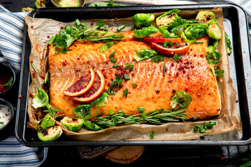 Cooked seafood on a black background. Baked salmon with onion, lemon, pomegranate juice