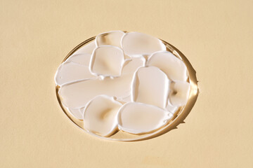 A smear of white cream on a beige background on a round stand.
