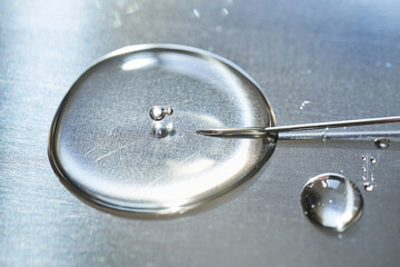 A drop of medicine flowing from a syringe with a needle.