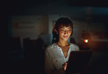 Typing, night and business with woman, tablet and happy with project, deadline and schedule. Technology, evening and creative agency with employee, consultant for graphic design or dark with internet