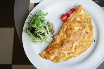 Plain Egg Omelette served with cherry tomato and herbs on table 