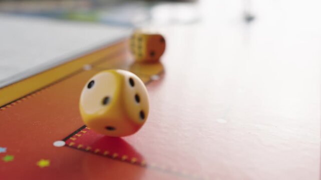 The hand throws yellow dices on the playing field. Gaming moments in dynamics. Luck and excitement. Board games strategy. Slow motion.