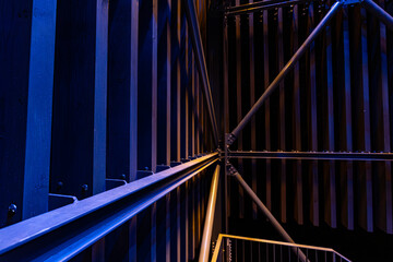 A close-up, abstract view of metal beams and structures illuminated with blue and yellow lights....