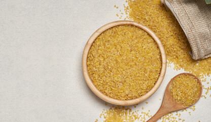 top view flat lay pile of bulgur or burghul wheat on table white background in wood bowl with copy space
