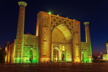 Ulugbek Madrasah on Registan Square illuminated at night.