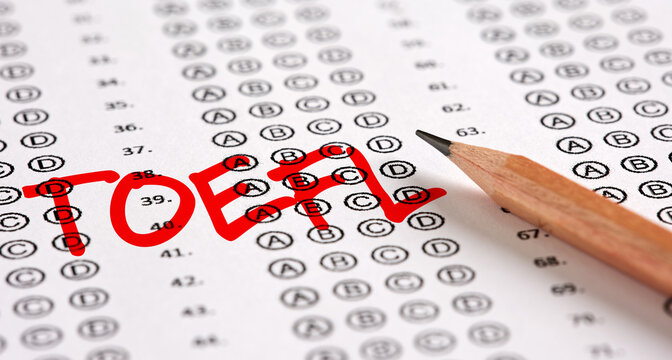 Close up view of an exam paper with the word TOEFL test of English as a Foreign Language and a pencil.