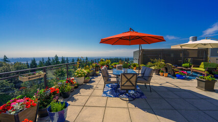Umbrella casting a wide shadow on a large rooftop patio garden on a bright summer day.