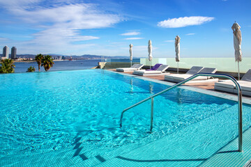 Open-air pool with turquoise clear water and sun loungers overlooking the Mediterranean coastline...