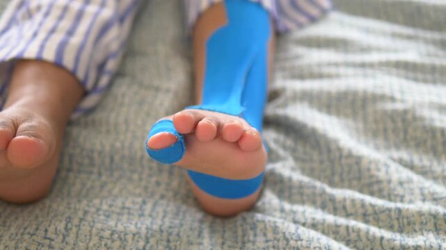 Elastic therapeutic blue tape applied to child leg. Kinesio Taping therapy for injury