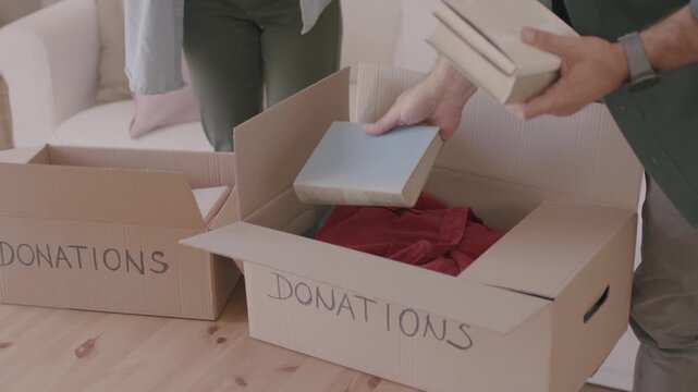 Young couple packing things in boxes. packing, donations, moving, new beginning concept. 4K video
