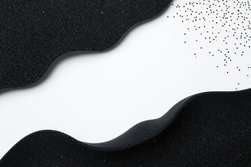 Fototapeta premium Elegant black curves against a contrasting white background, adorned with shimmering specks, creating a visually striking and modern abstract design.