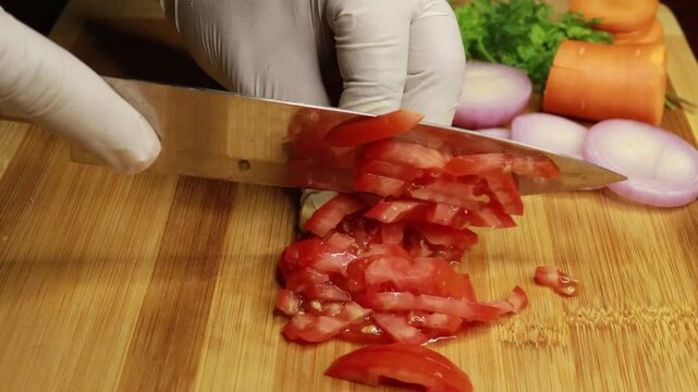 Women cutting fresh tomatoes with a knife into slices on a wooden cutting board. Cooking meal concept.
