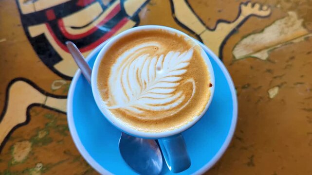 Beautiful golden flat white coffee with latte art in a blue cup and saucer, top down, at local cafe in Wellington, New Zealand