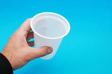 A man's hand holds a plastic cup.