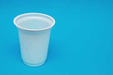 White plastic drink glass on blue background.