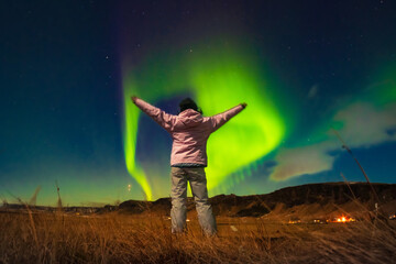 Woman watches the northern lights arms up excited joyful in Iceland. Woman in Icelandic spring...