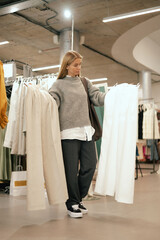 Middle aged woman choosing clothes in a clothing store. Sale promotion and shopping concept. Part of the series