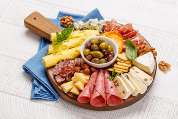 A selection of various cheeses and meats arranged on a wooden board