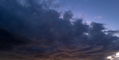 Tropical sunset. Beautiful sunset sky with clouds. Orange sunset, dark clouds in sky. Background of dark clouds before storm. Dramatic clouds. Apocalyptic sky, dark cloud. Overcast Dramatic sky.