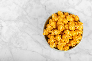 Sweet caramel popcorn in a bowl on a wooden background. Salted caramel popcorn. Caramel sauce. Close up. Topping. Place for text. Copy space