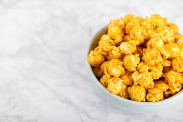 Sweet caramel popcorn in a bowl on a wooden background. Salted caramel popcorn. Caramel sauce. Close up. Topping. Place for text. Copy space