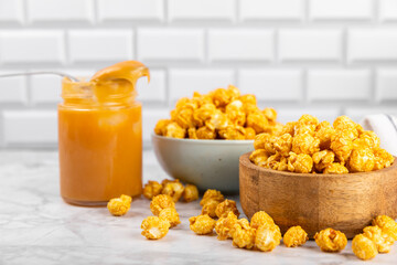 Sweet caramel popcorn in a bowl on a wooden background. Salted caramel popcorn. Caramel sauce. Close up. Topping. Place for text. Copy space