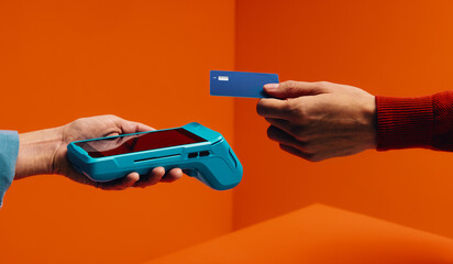 Cashless payment with a credit card and wireless card processor against bright orange background